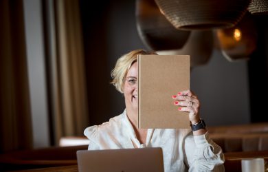 vrouw houdt notitie boekje voor haar gezicht waar goede voornemens in staan